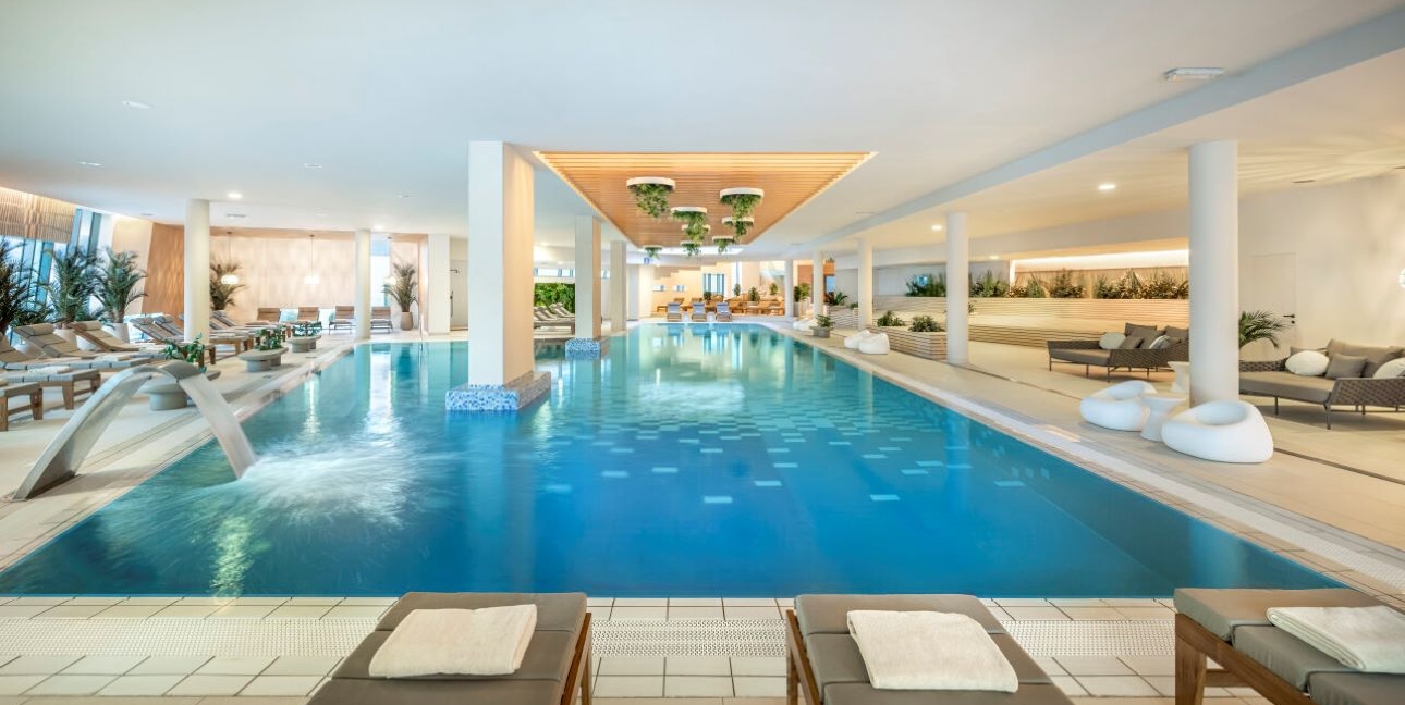 pool in spa area with sofas and loungers around it