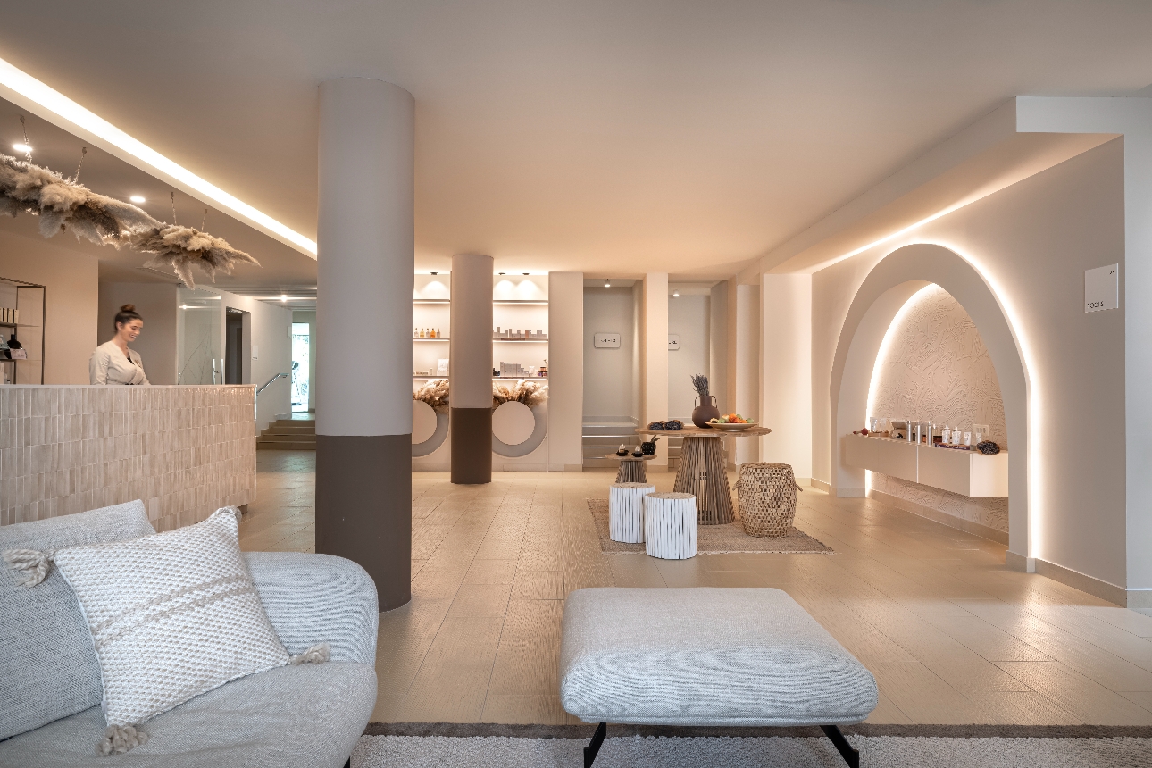 spa reception area, neutral tones, products on shelves, sofas